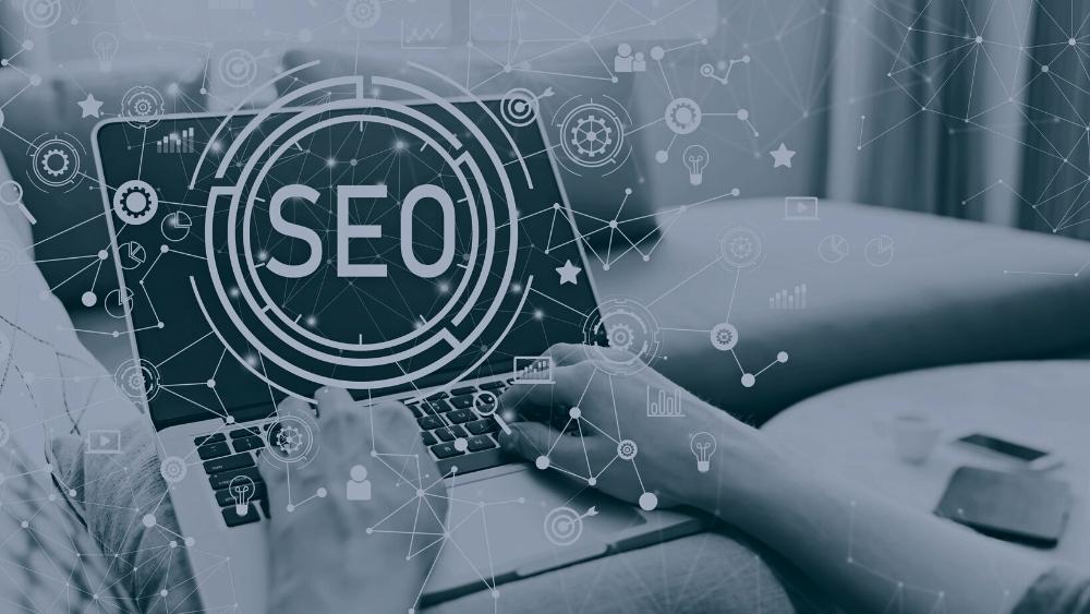 A person on a laptop with a web of SEO icons.